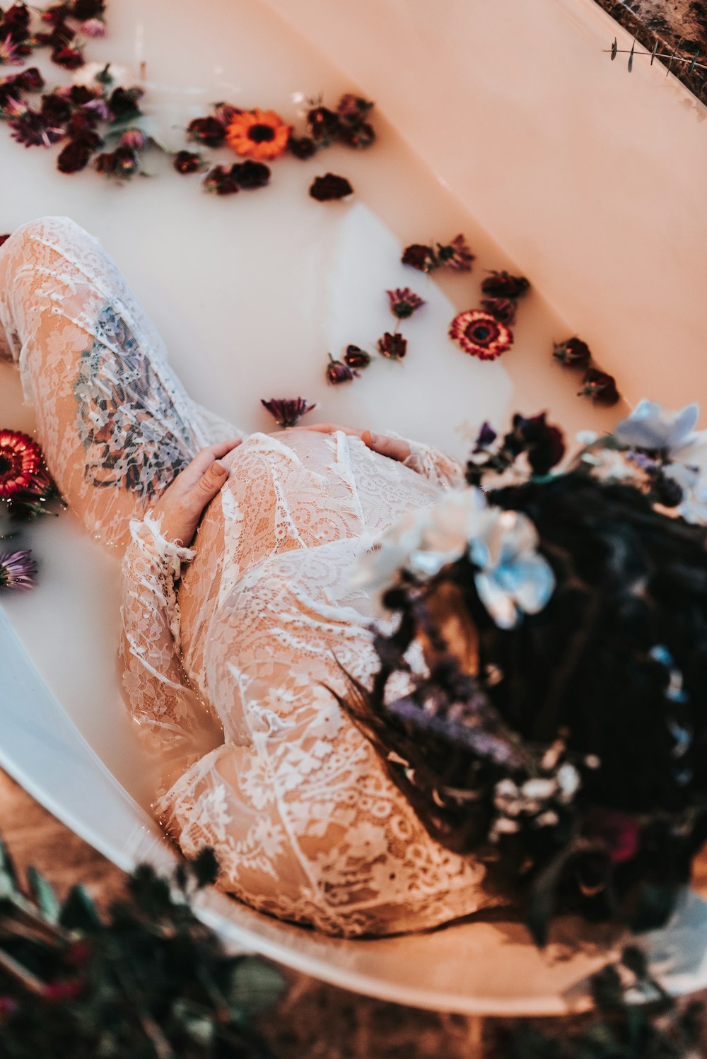 pregnant woman sitting on bath tub with flowers