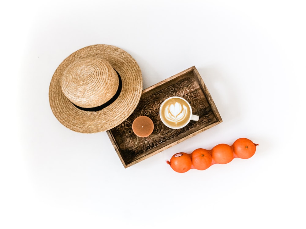 brown wicker hat besides white coffee mug