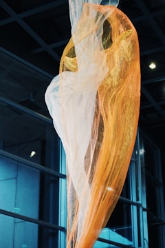 A vibrant installation of suspended translucent fabrics moving gently in air.