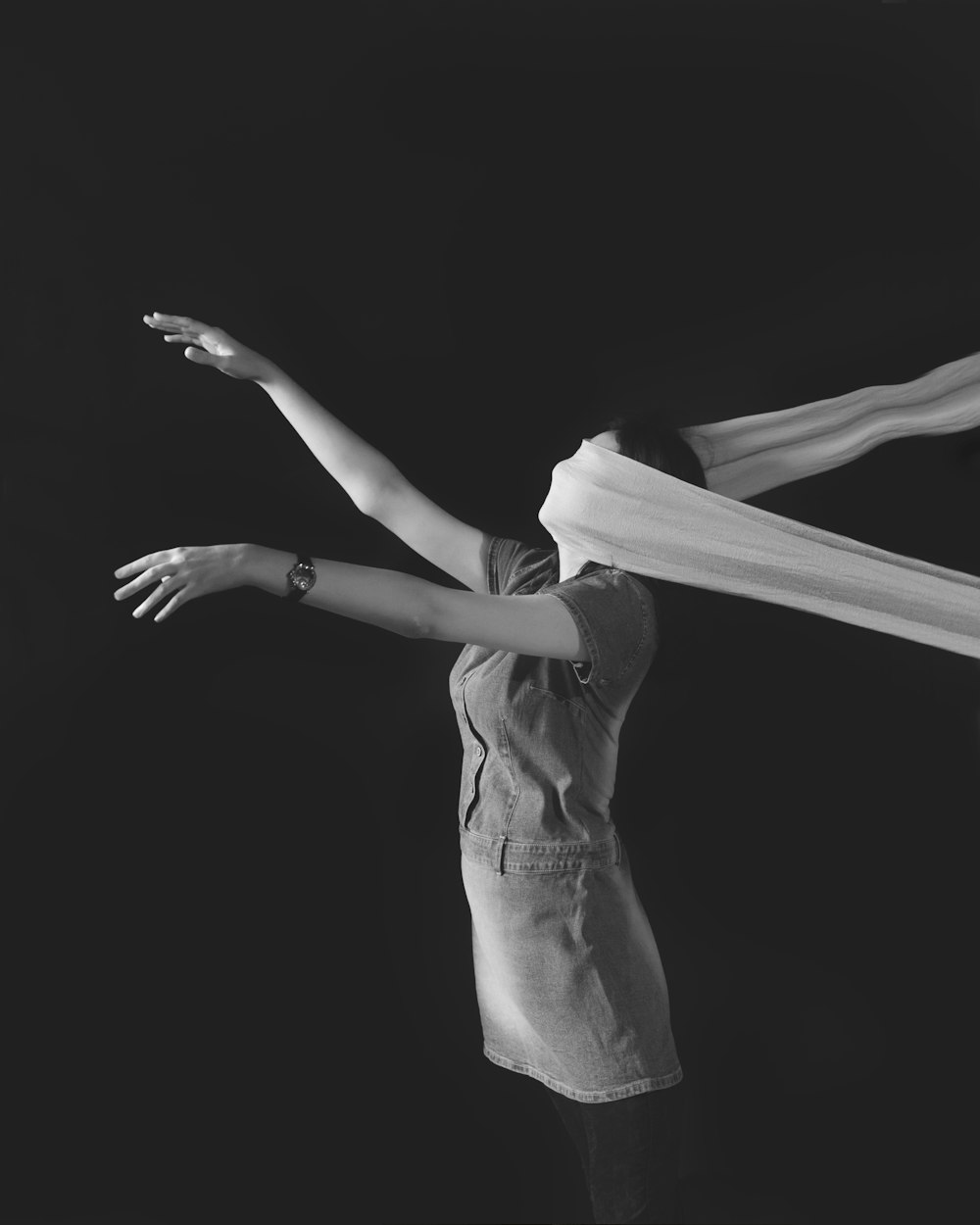 woman raising both hands with white textile on face