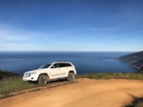 Spacious white SUV on a coastal road overlooking the ocean.