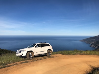 Spacious white SUV on a coastal road overlooking the ocean.