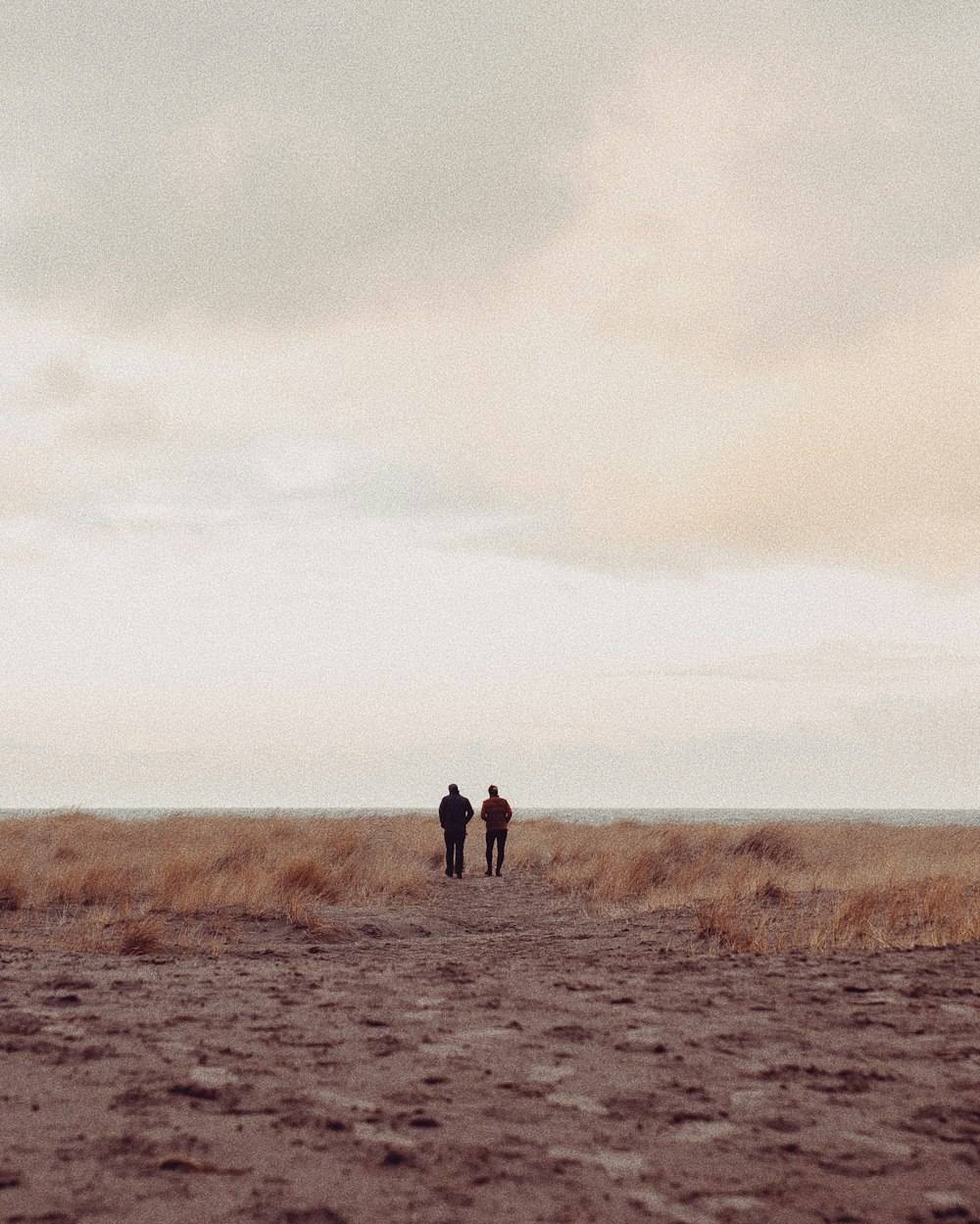 two people standing on sand