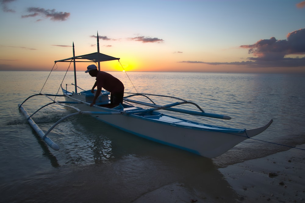 man standing on white and blue boat