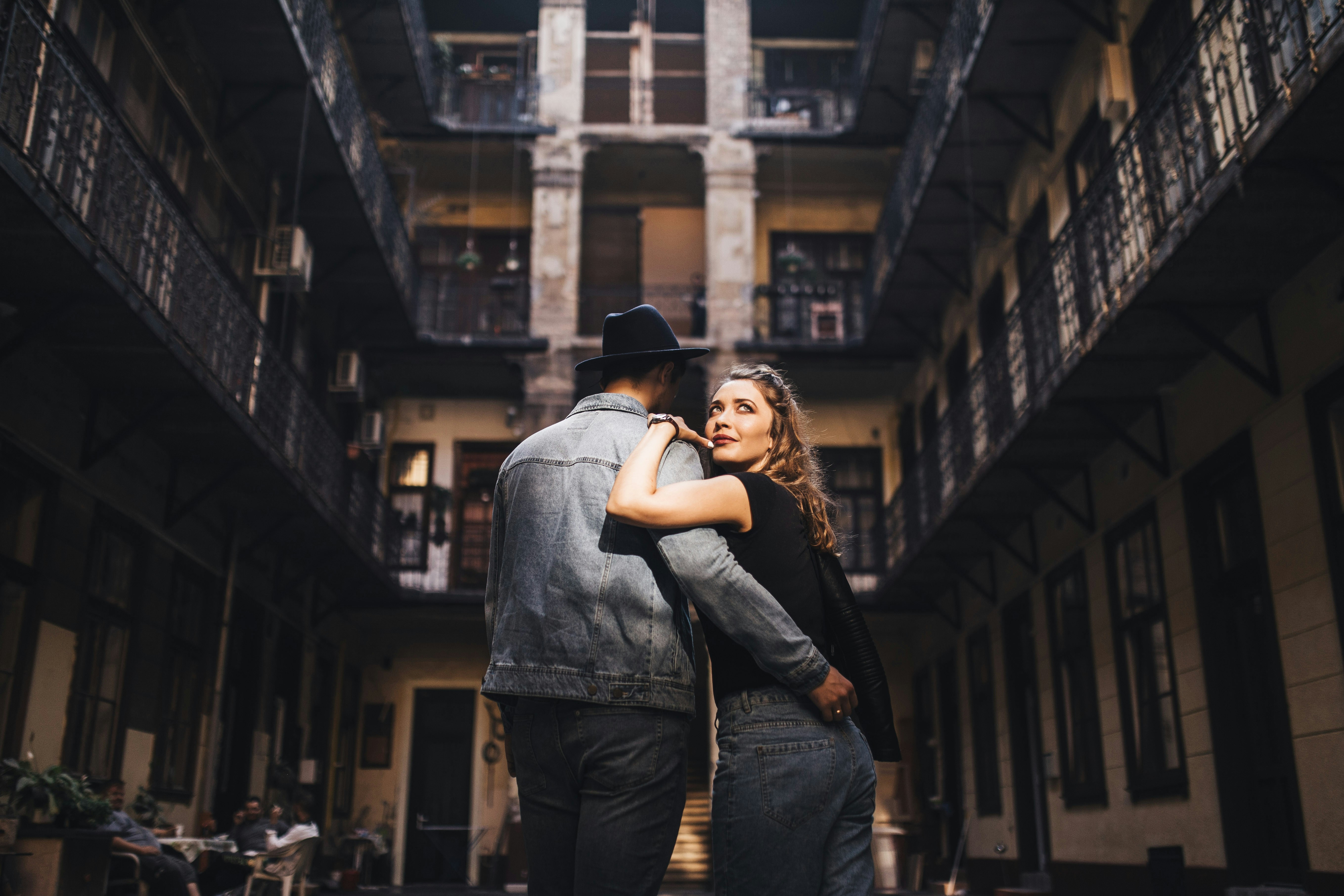 man wearing gray jacket holding woman wearing black top