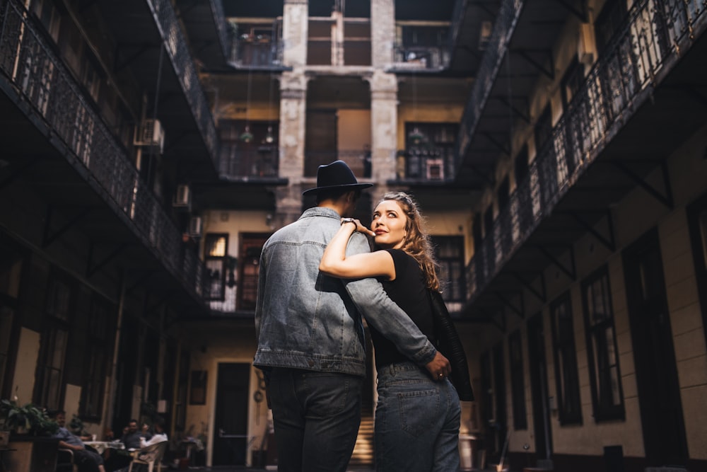 man wearing gray jacket holding woman wearing black top