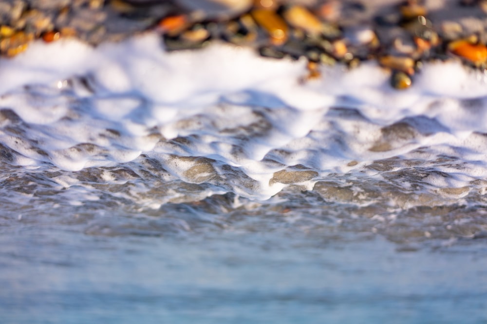 a close up of a wave with rocks in the background
