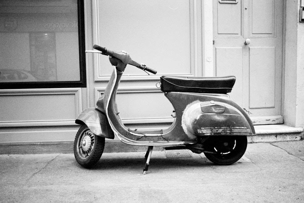 gray motor scooter parked beside wall