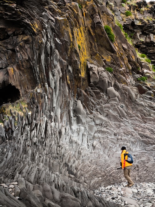 man standing walking on cave in Hellnar Iceland