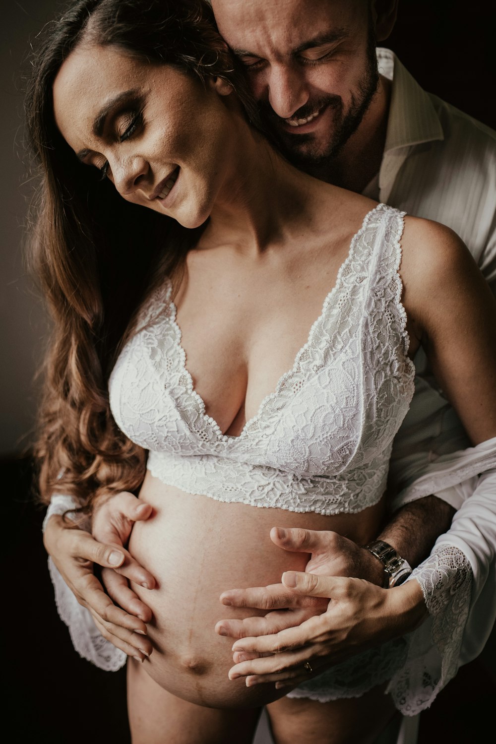 man hugging pregnant woman both smiling