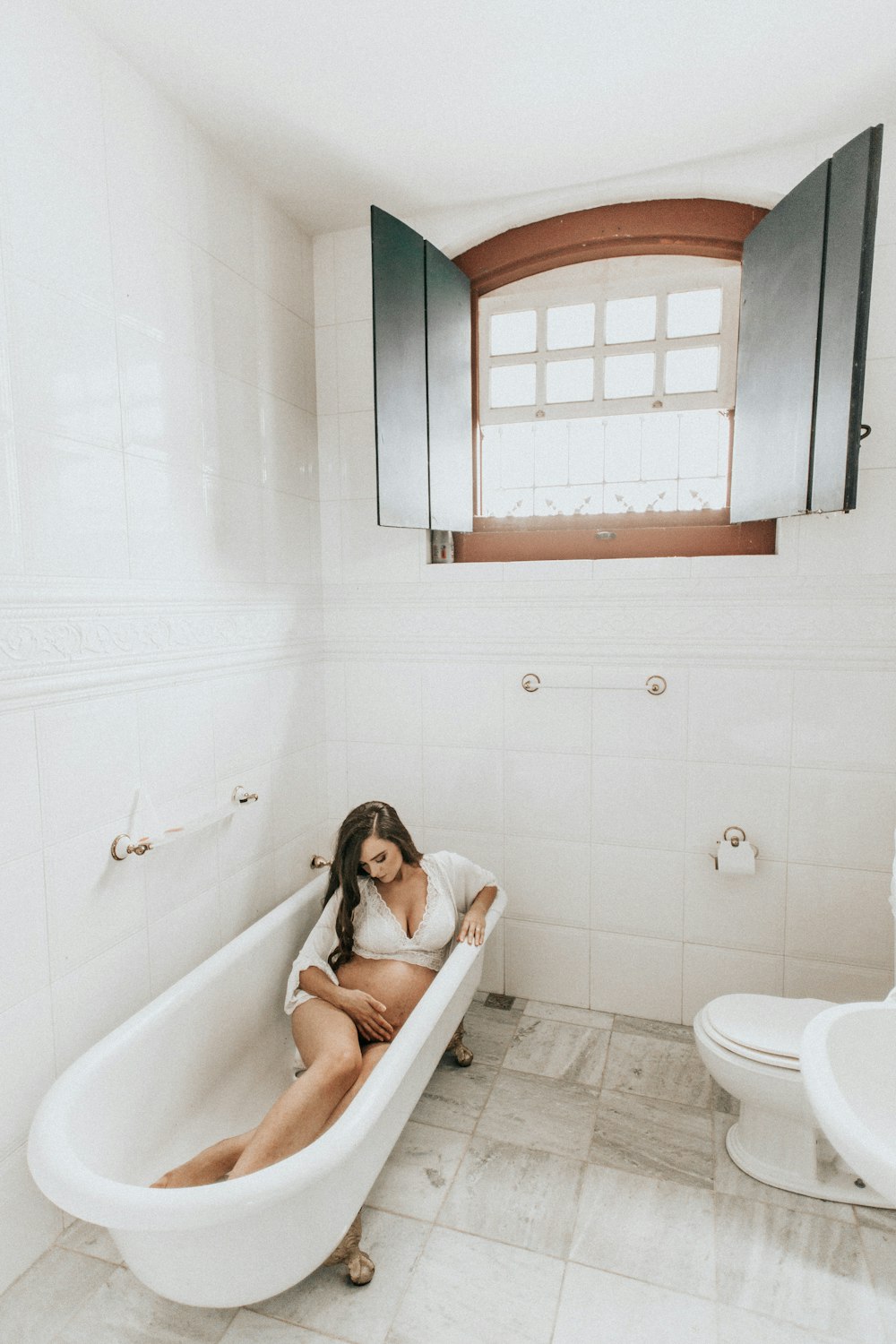 woman lying in bathtub holding tummy