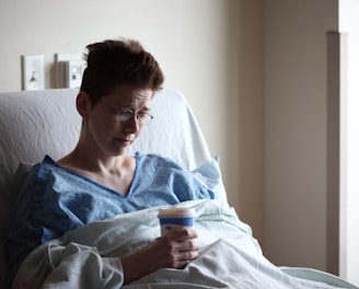 woman on bed holding plastic cup