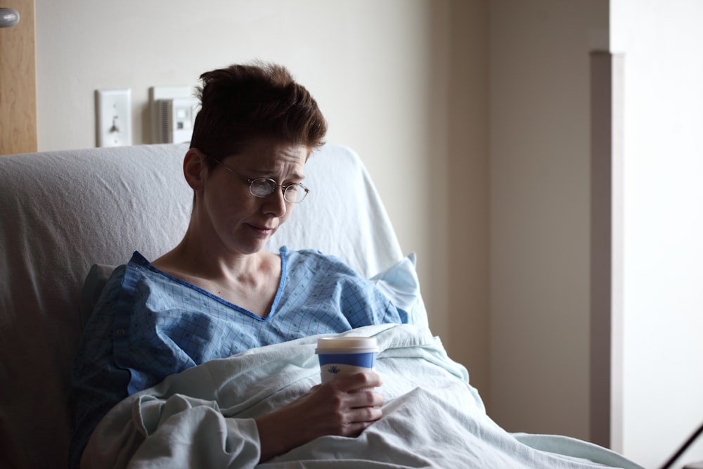 mujer en la cama sosteniendo un vaso de plástico