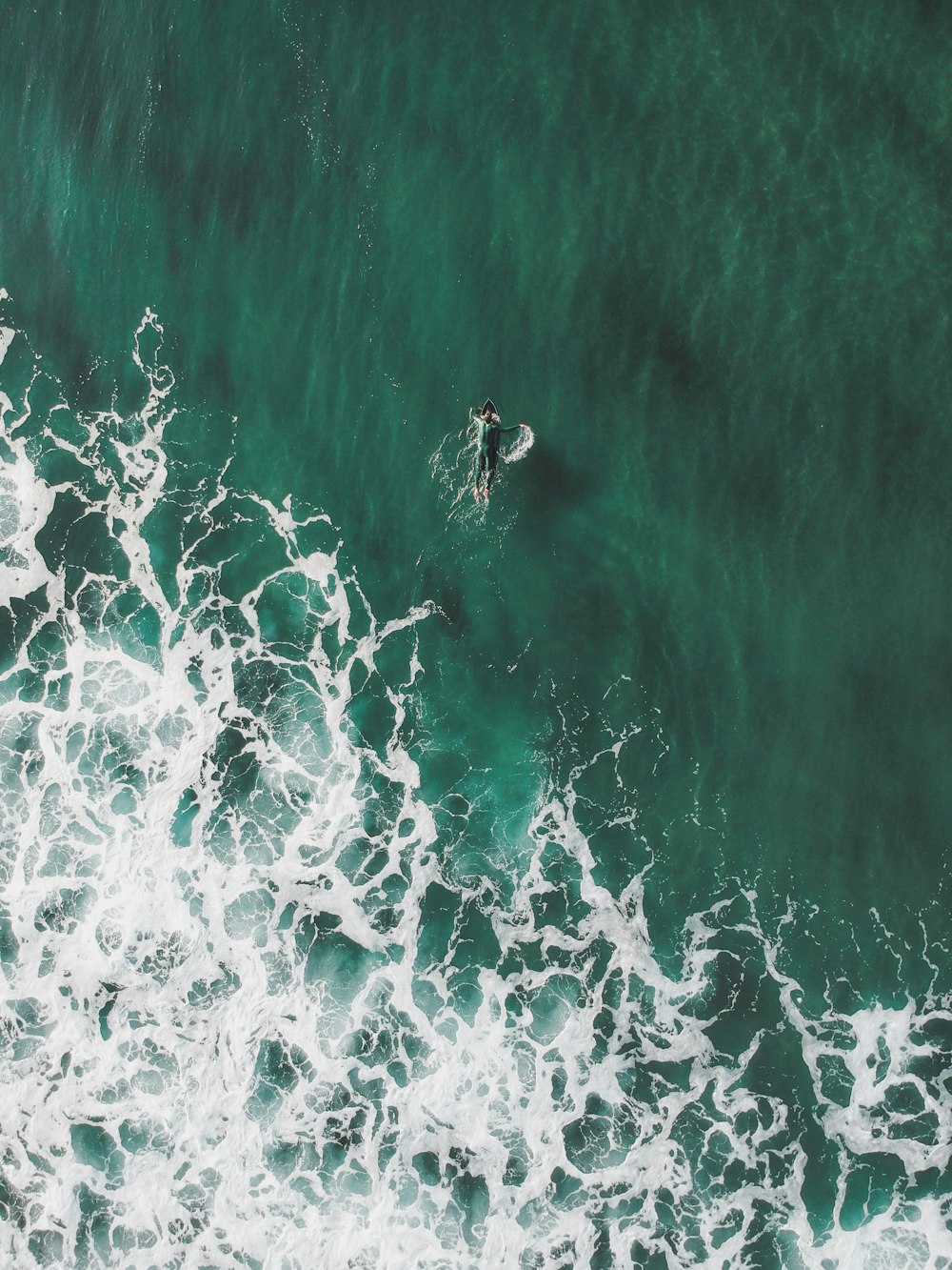 aerial view of man swimming into the ocean