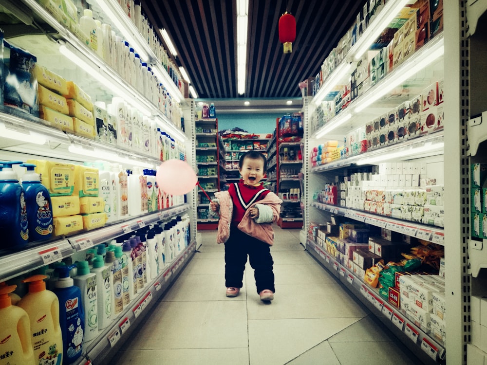baby walking between white shelves