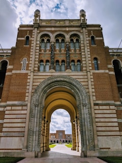 brown and white concrete arch building under dramatic clouds during daytime