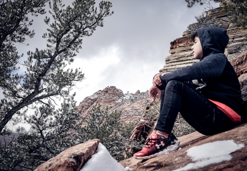 man sitting on brown rock formation