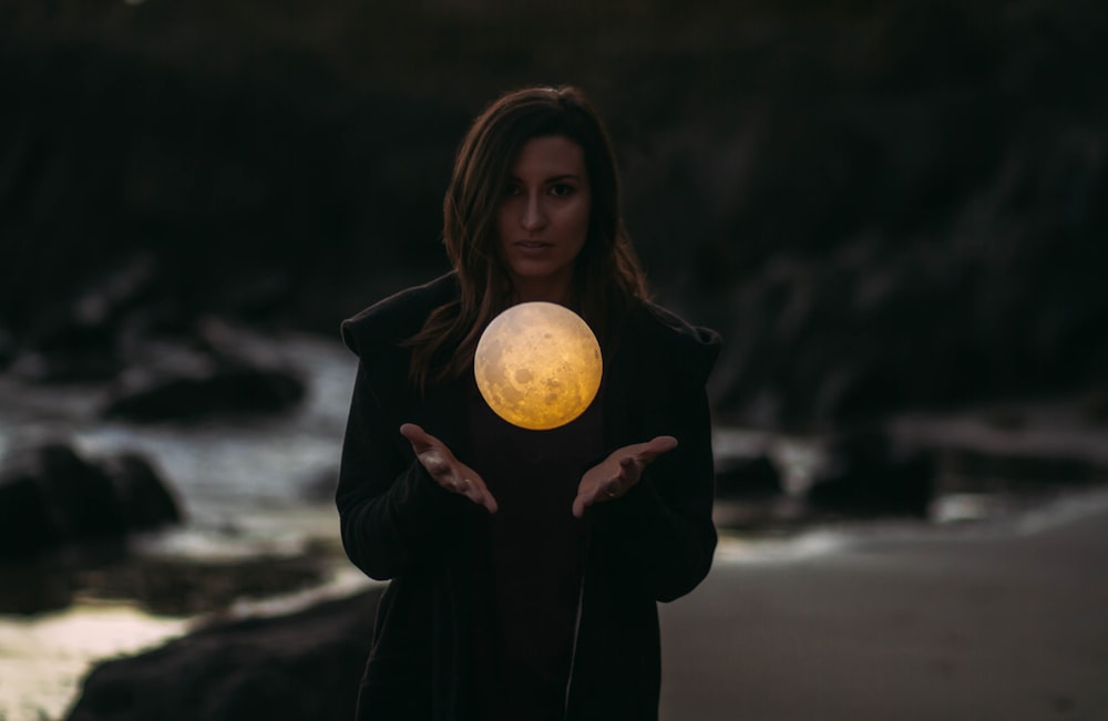 woman wearing black jacket standing near water