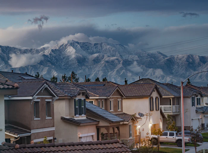 Rooftops of a hillside neighbourhood below mountains