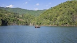 Visitors enjoying a serene boat ride on a crystal-clear lake surrounded by lush greenery.