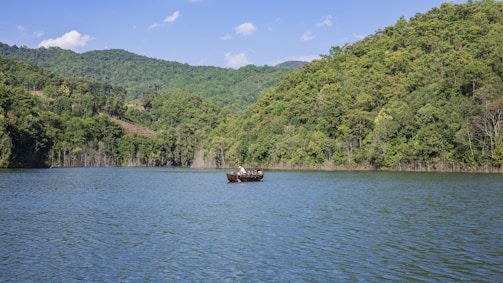 Guests enjoying a peaceful boat ride on the lake surrounded by lush green hills.