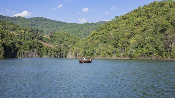 Tourists enjoying a boat ride on the serene Lake Maninjau with hills in the background