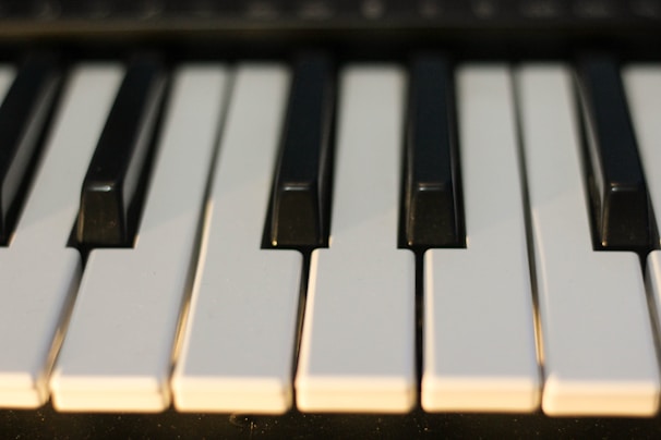 A close-up view of several piano keys, showing a combination of black and white keys in a slightly staggered, diagonal arrangement.