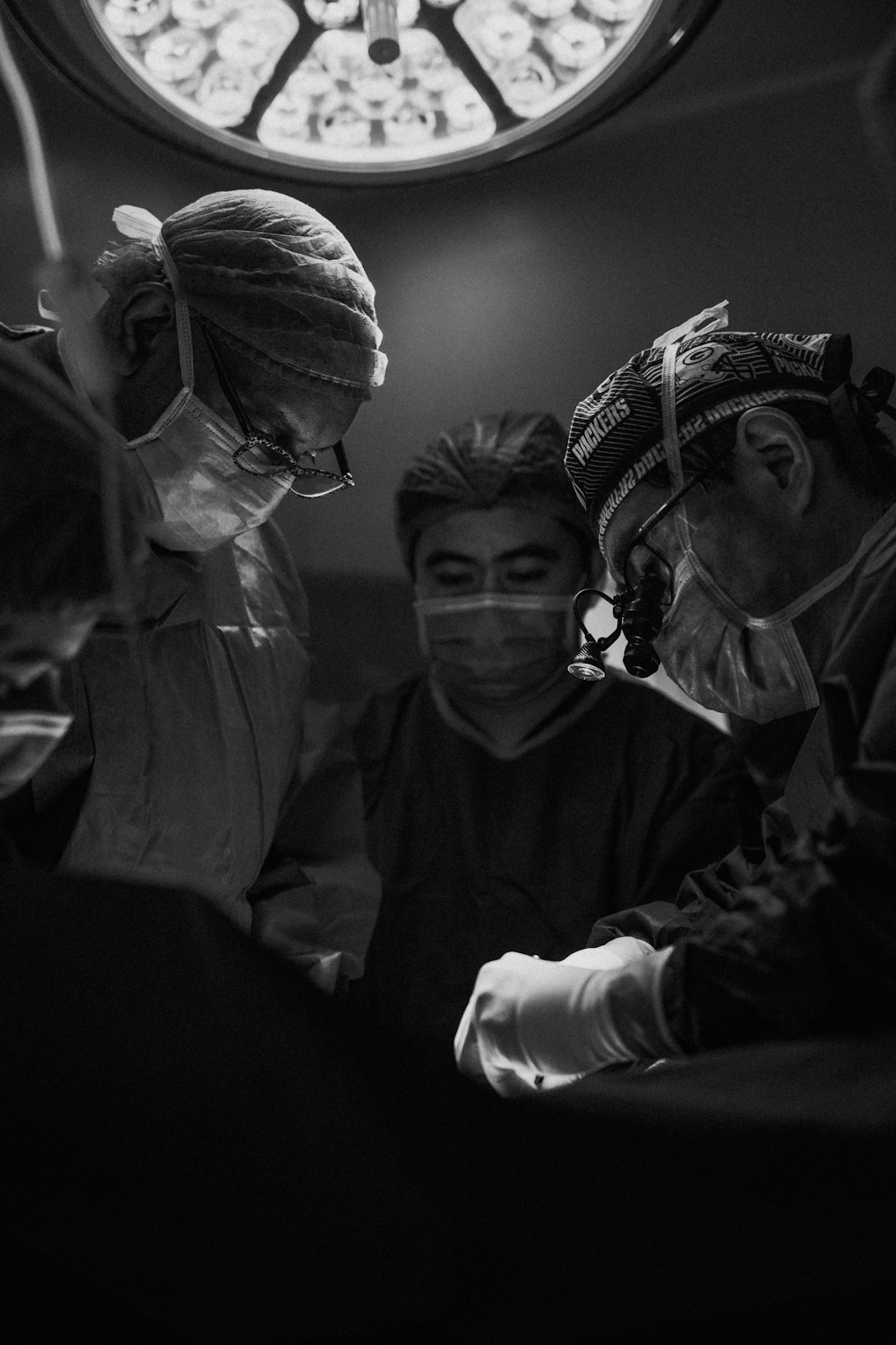 Foto en escala de grises de tres enfermeras y un médico a punto de realizar una cirugía