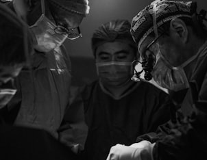 gray scale photo of three nurses and doctor about to perform surgery