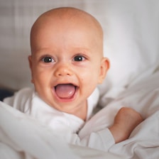 baby smiling on white cushion