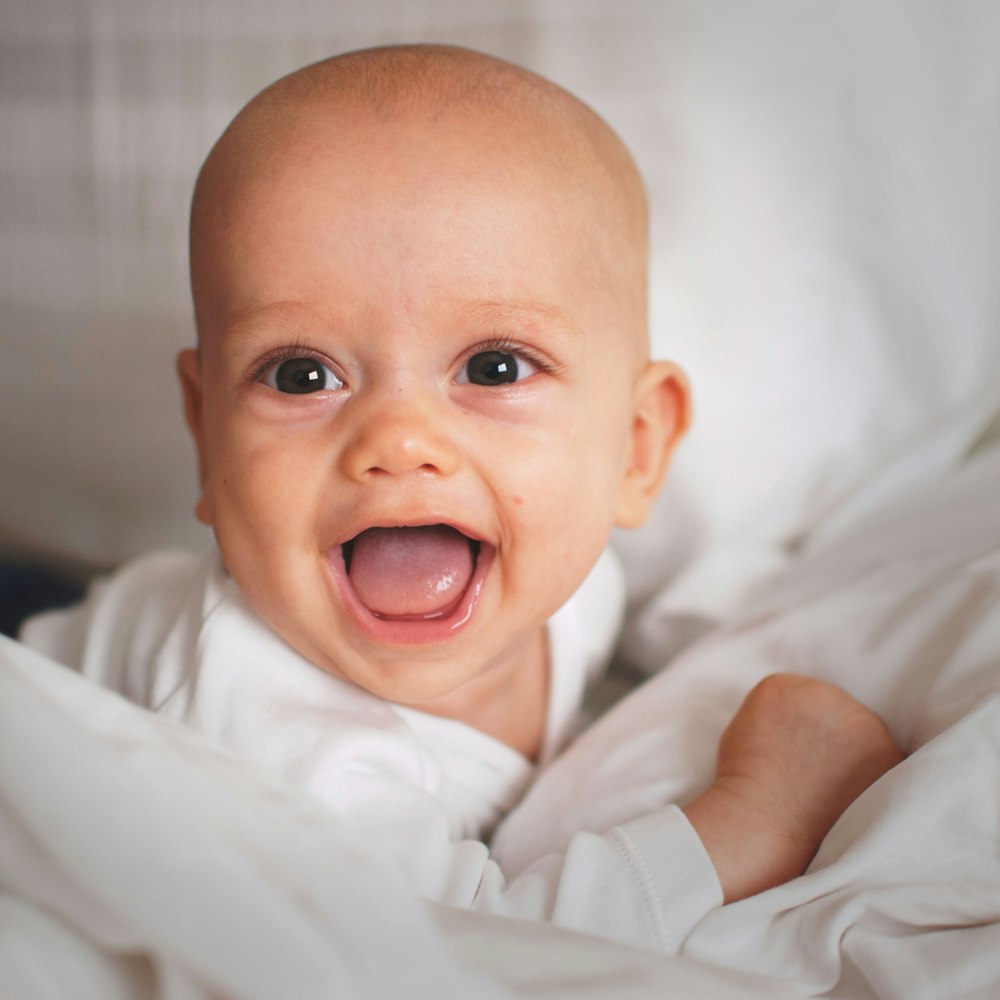 baby smiling on white cushion