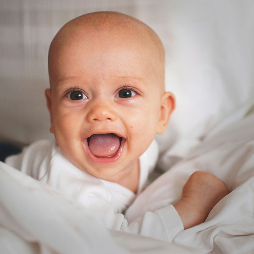 bebé sonriendo en cojín blanco