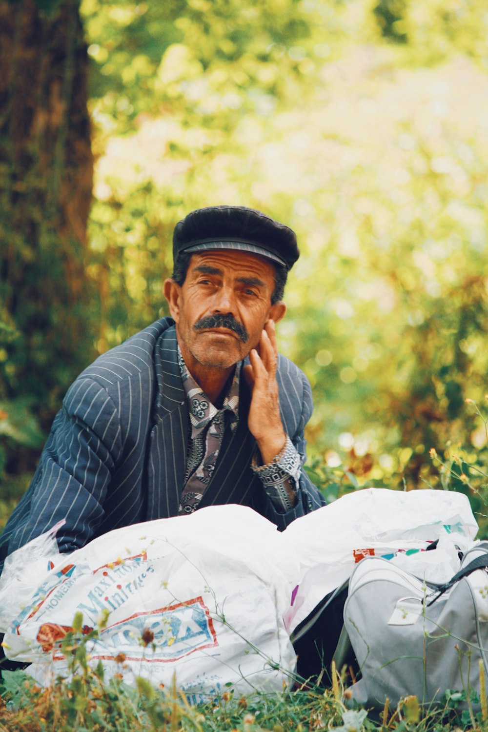 야외 푸른 잔디밭에 앉아있는 모자를 쓴 남자