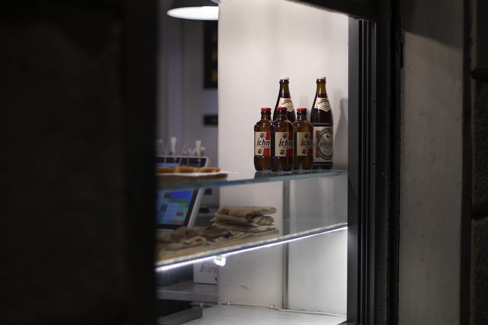 four clear glass liquid bottles on beverage cooler