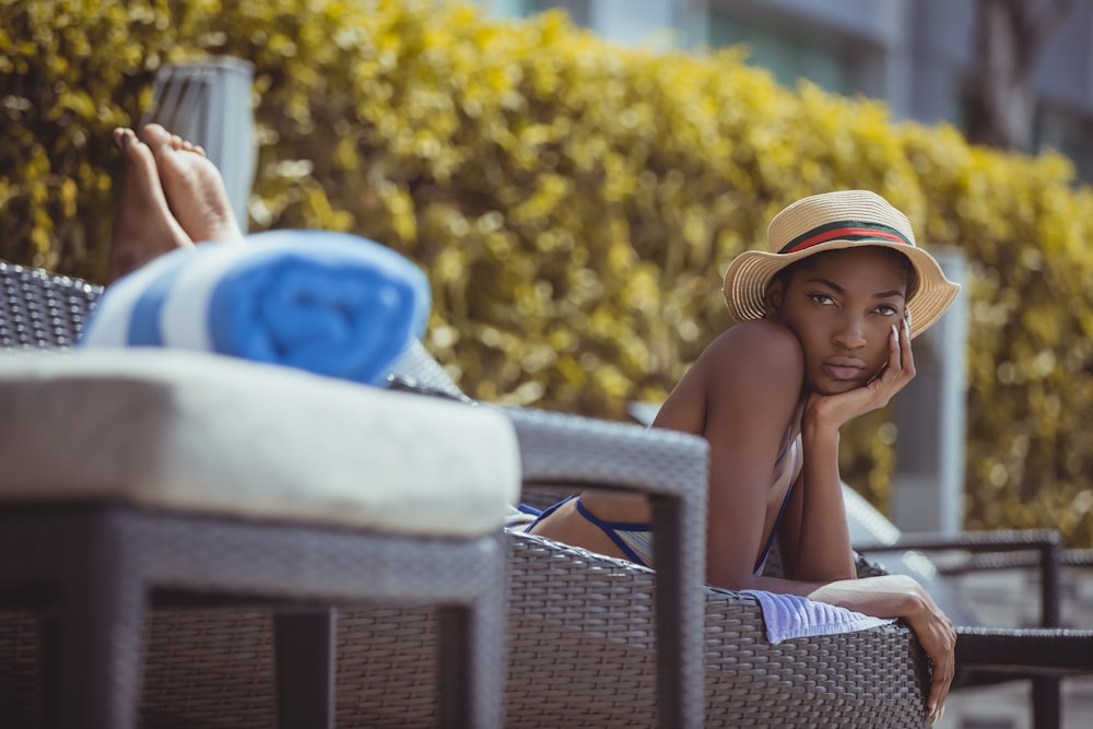 woman lying on brown wicker bench