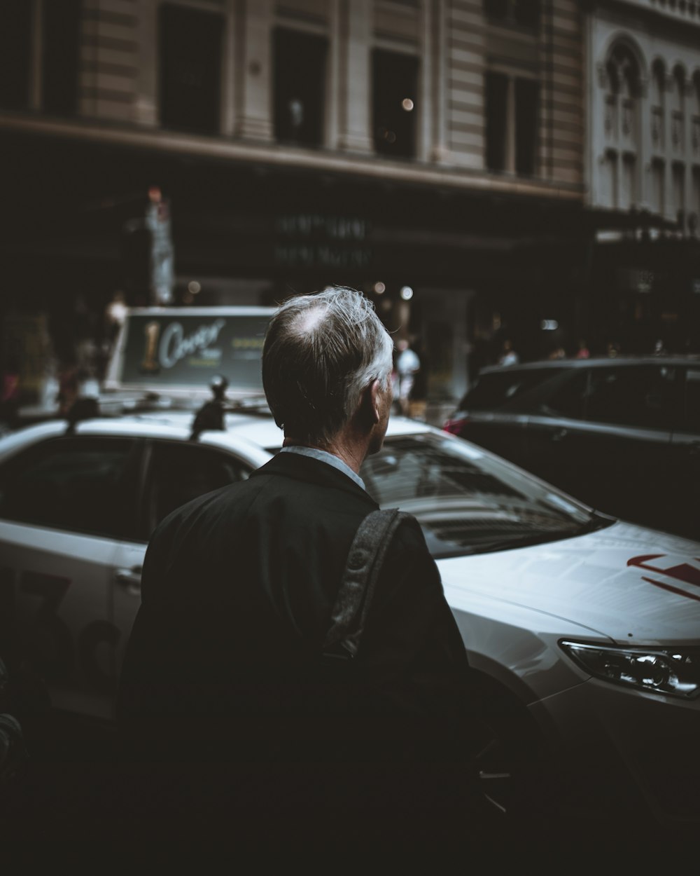 man facing silver sedan