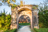 An ancient stone archway framed by lush greenery under soft sunlight.