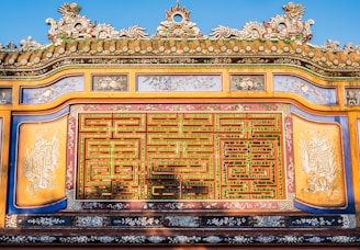 An ornate, colorful architectural detail with intricate patterns and carvings, featuring a harmonious blend of greens, reds, and yellows. Traditional motifs and symbology are incorporated into the design.