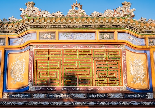 An ornate, colorful architectural detail with intricate patterns and carvings, featuring a harmonious blend of greens, reds, and yellows. Traditional motifs and symbology are incorporated into the design.