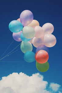 Colorful party balloons floating against a bright blue sky
