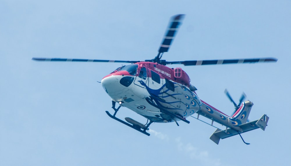 white, red, and gray helicopter flying