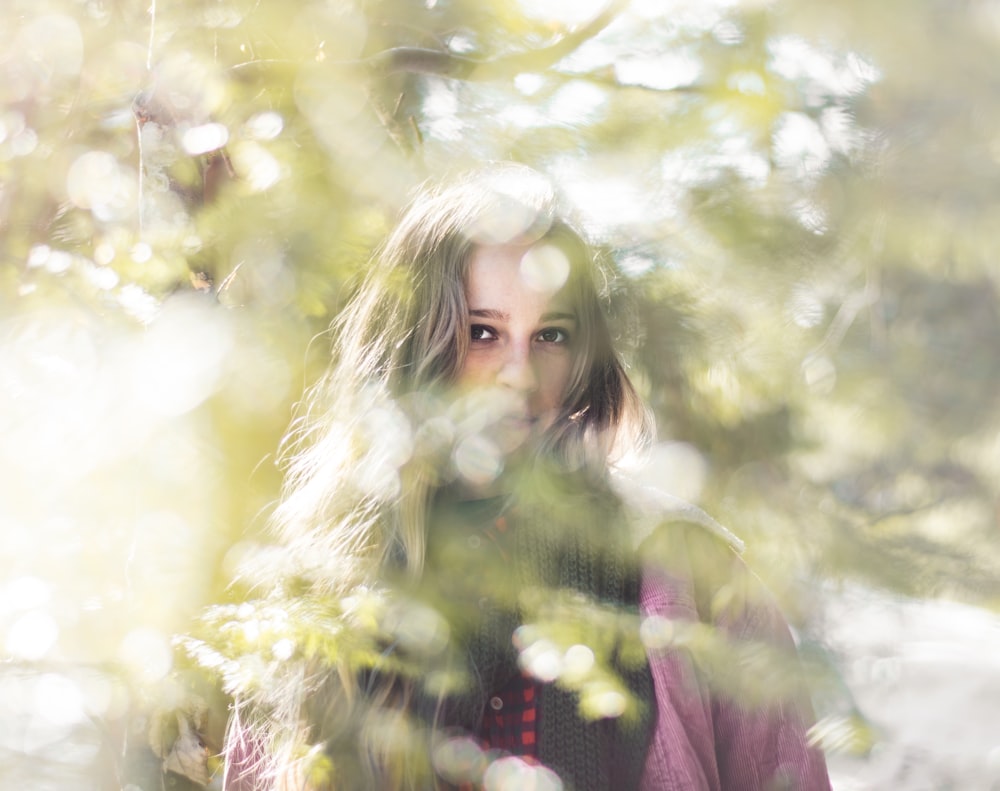 woman in purple shirt see through the gap of leaves