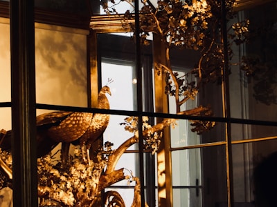 Elegant antique metal showpiece shaped like a peacock with detailed feather engravings on a wooden base.