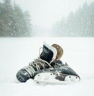 pair of black-and-white ice skates surrounded by snow