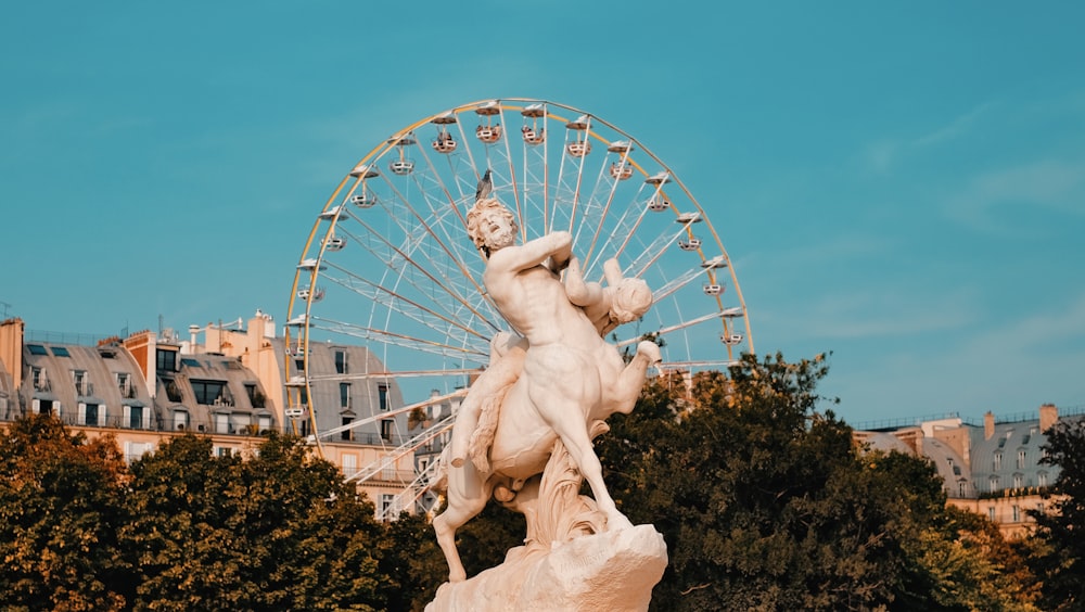 Centaur statue near trees with view of Ferris wheel during daytim