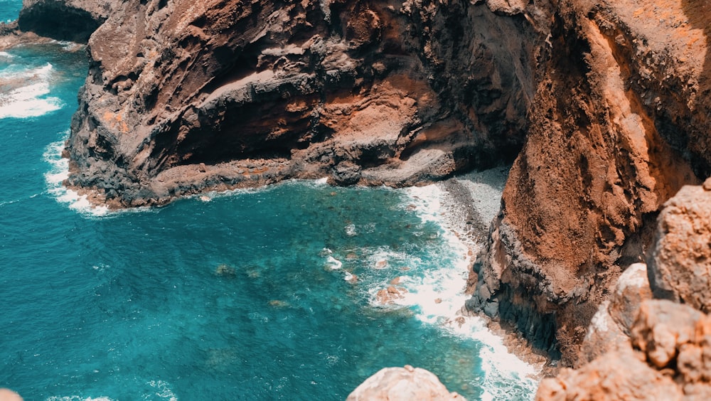 splashing on wave near rock formation during daytime