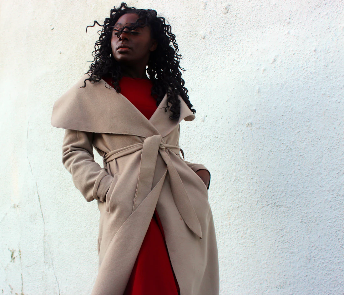 Femme en manteau beige à large col porté sur une robe rouge