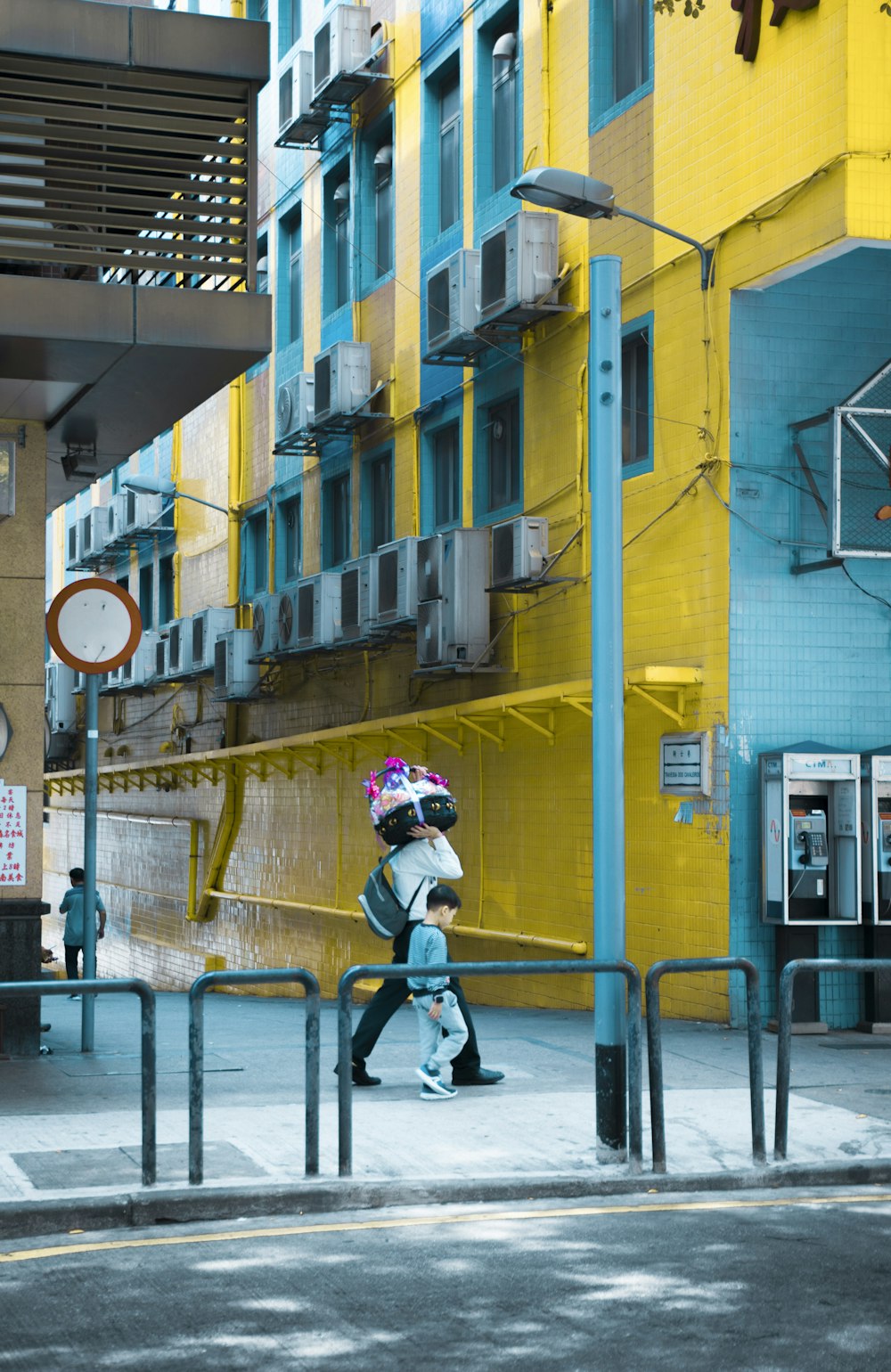 person carrying green backpack across yellow building