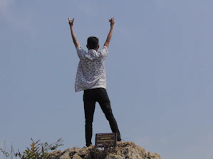 A confident individual celebrating a personal achievement with arms raised.