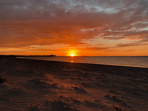 A serene view of Radhanagar Beach at sunset with turquoise waters and soft golden sand.